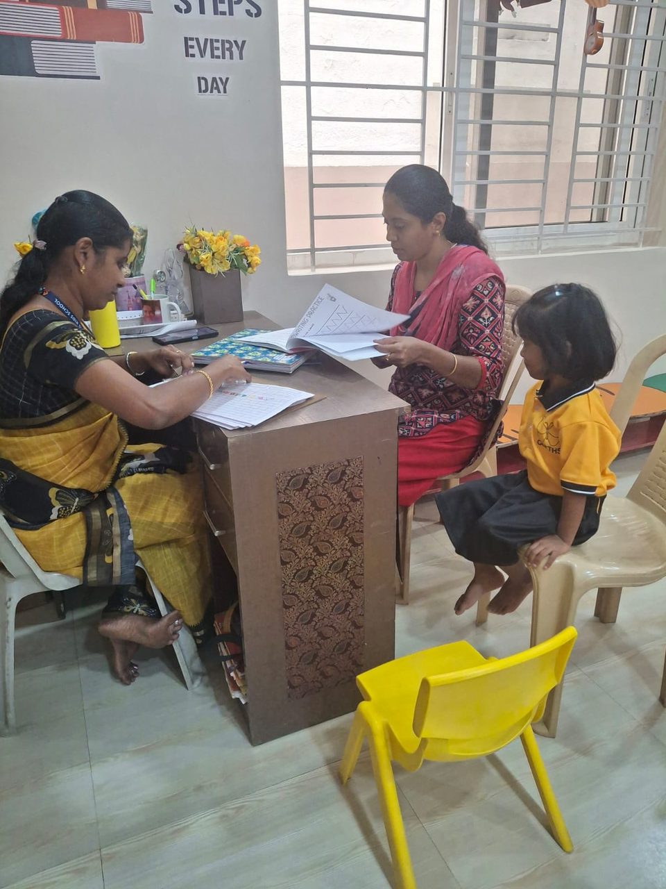 A teacher helping a parent and child with admission details at the school desk