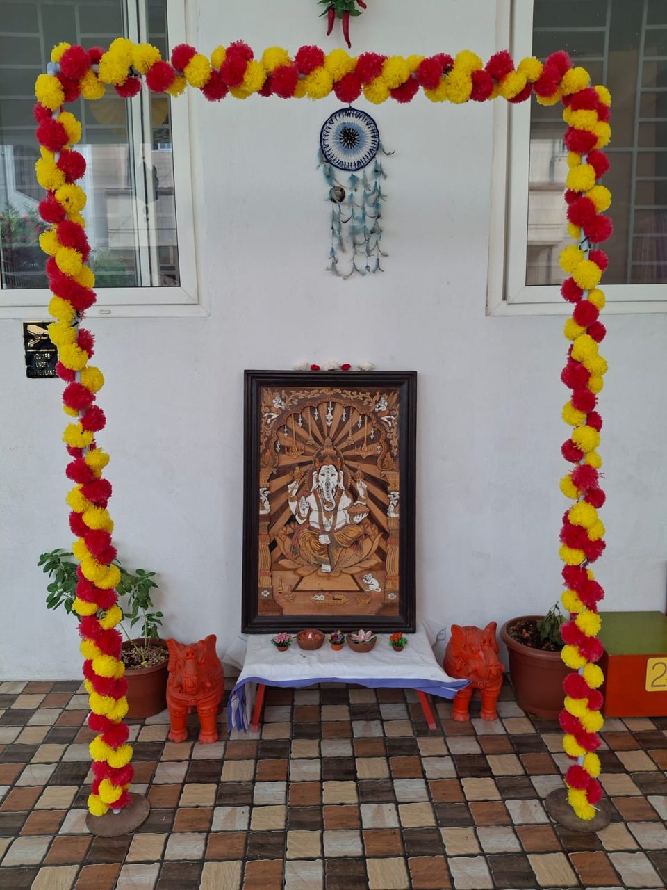 School entrance decorated with a flower garland and a carved deity panel